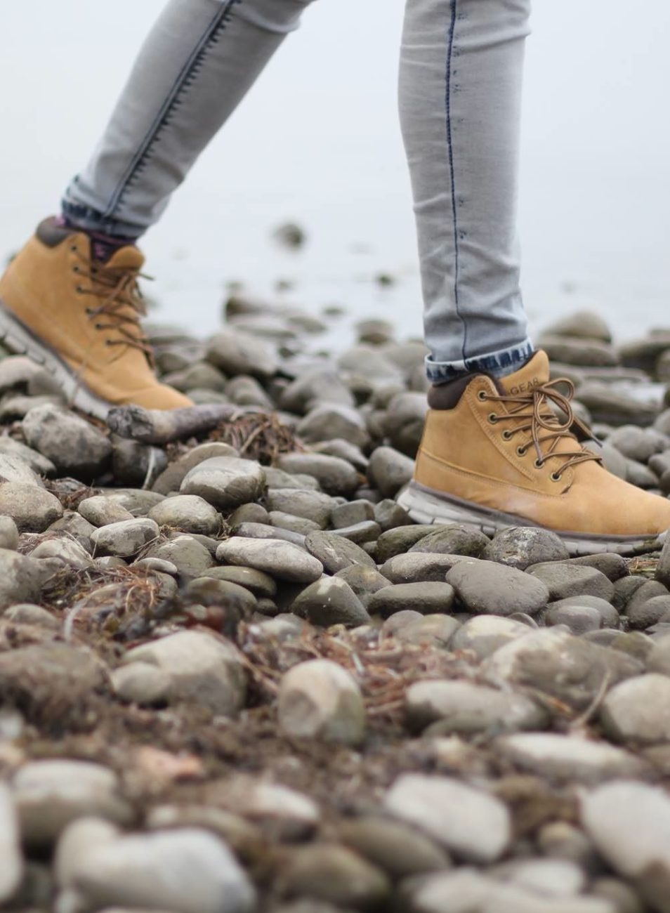 Person wearing tan boots walking on rocky terrain.